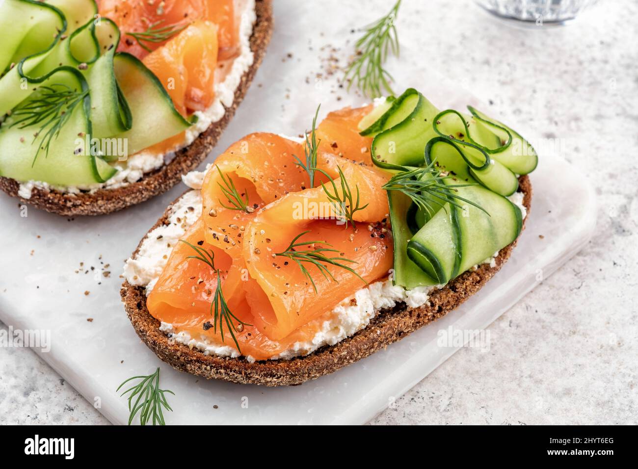Rye bread open sandwiches with salted salmon and cucumber on a white
