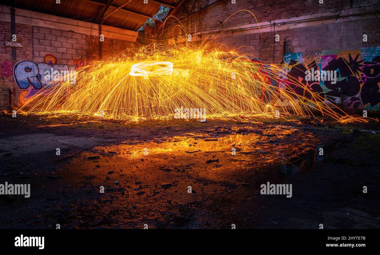 Showers of hot glowing sparks from spinning steel wool in a derilict old building Stock Photo