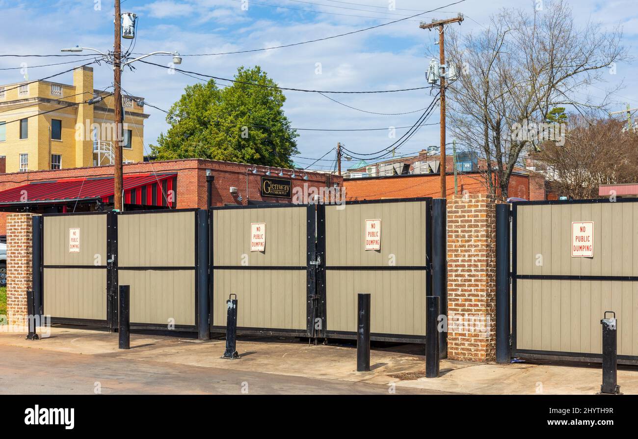 BELMONT, NC, USA-8 MARCH 2022: Row of dumpsters behind locked gates, with 'no public dumping' signs on each. Stock Photo