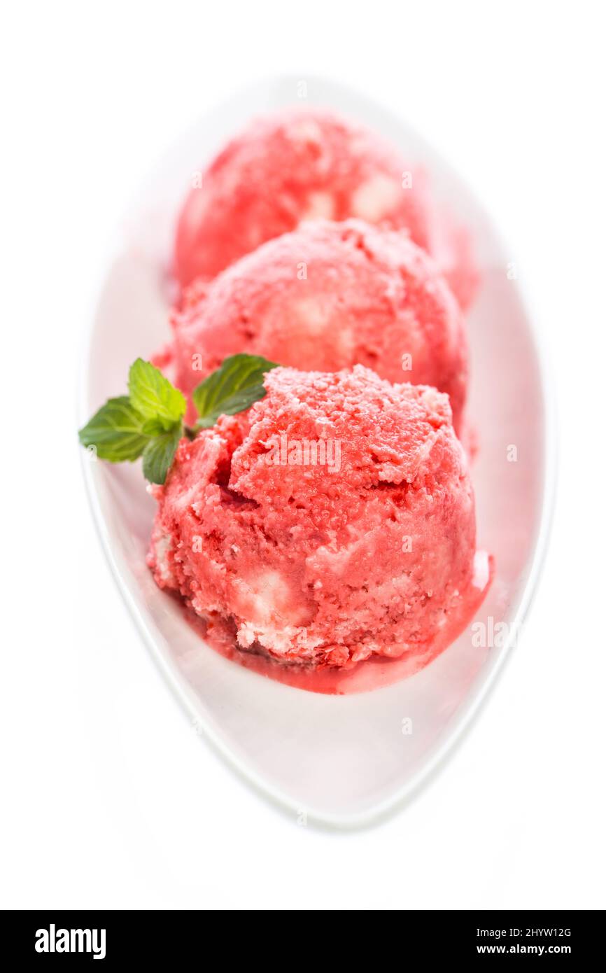 Three scoops of strawberry ice cream with mint leaves in a bowl Stock Photo
