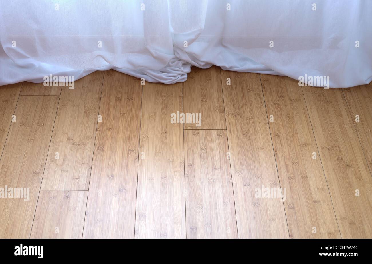 detail of a white curtain trailed on a bamboo parquet floor Stock Photo