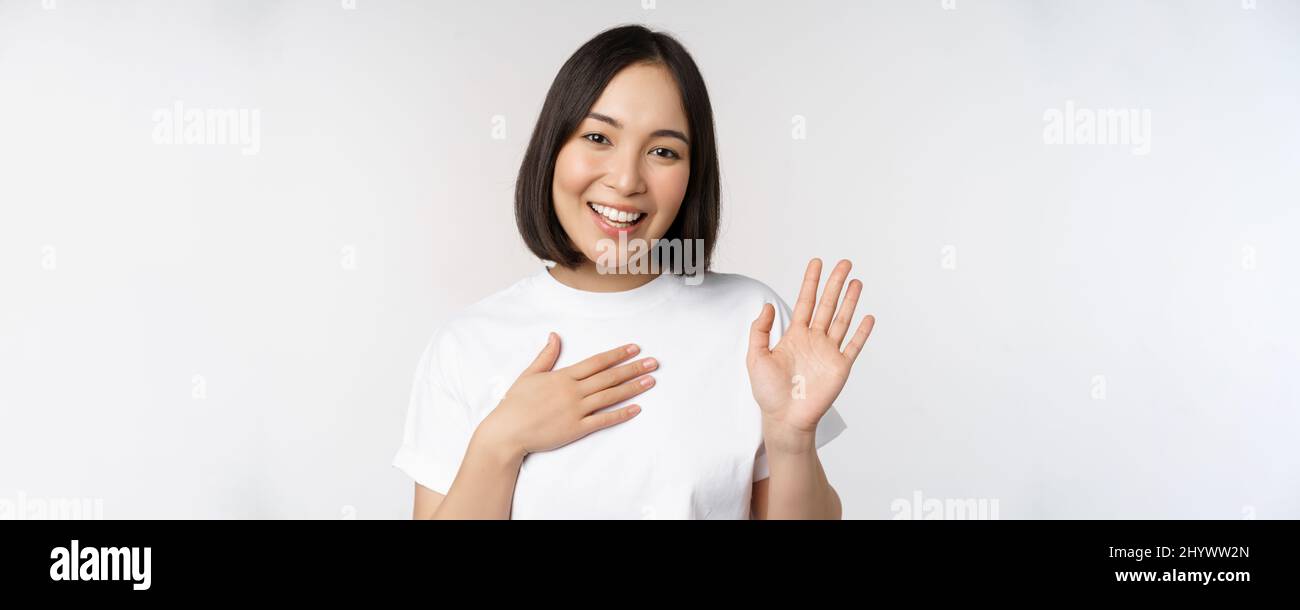 Portrait of beautiful korean girl raising hand, introduce herself, put