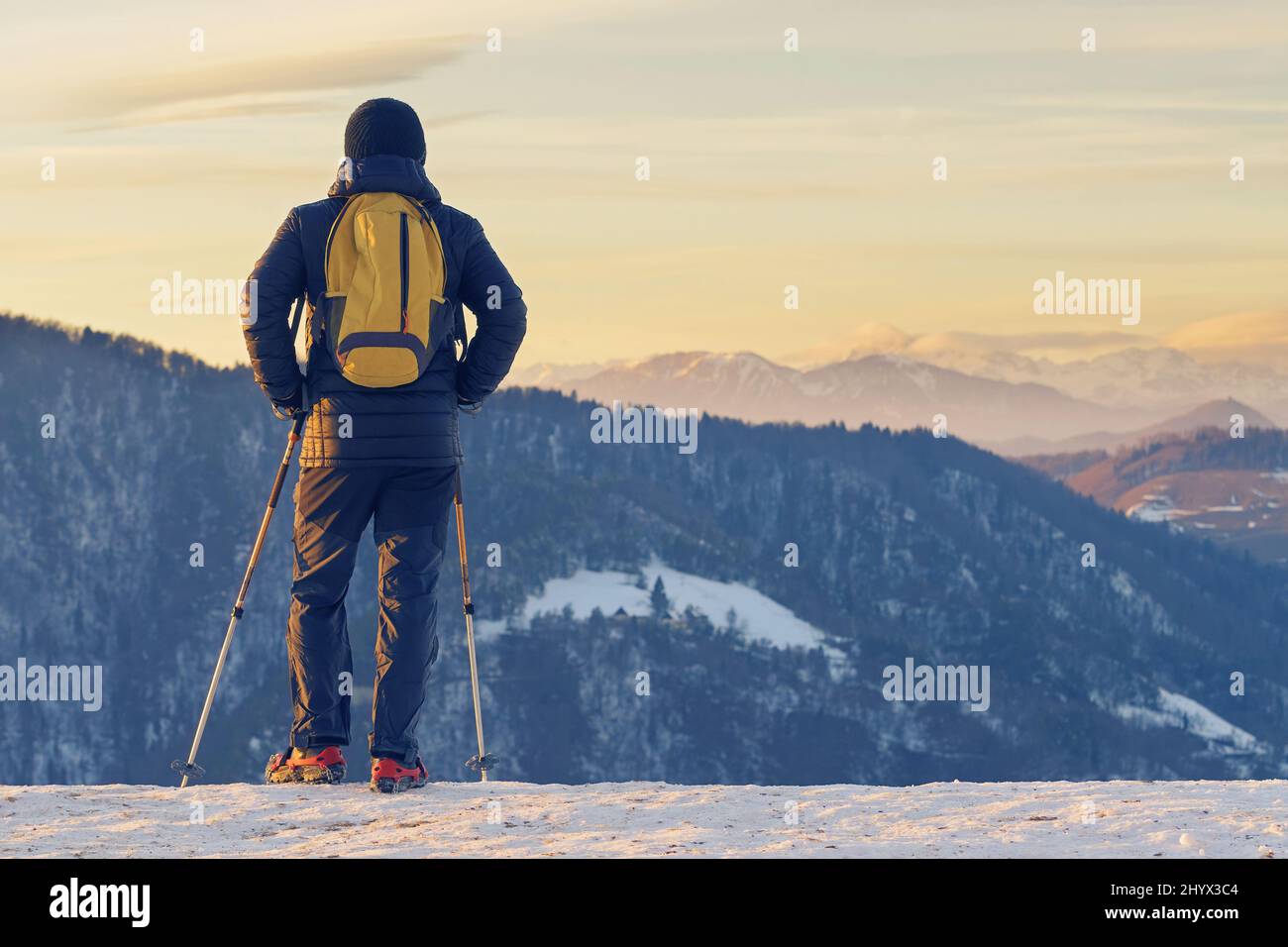 Hiker in snow gear enjoying the view of winter landscape at sunset time Stock Photo