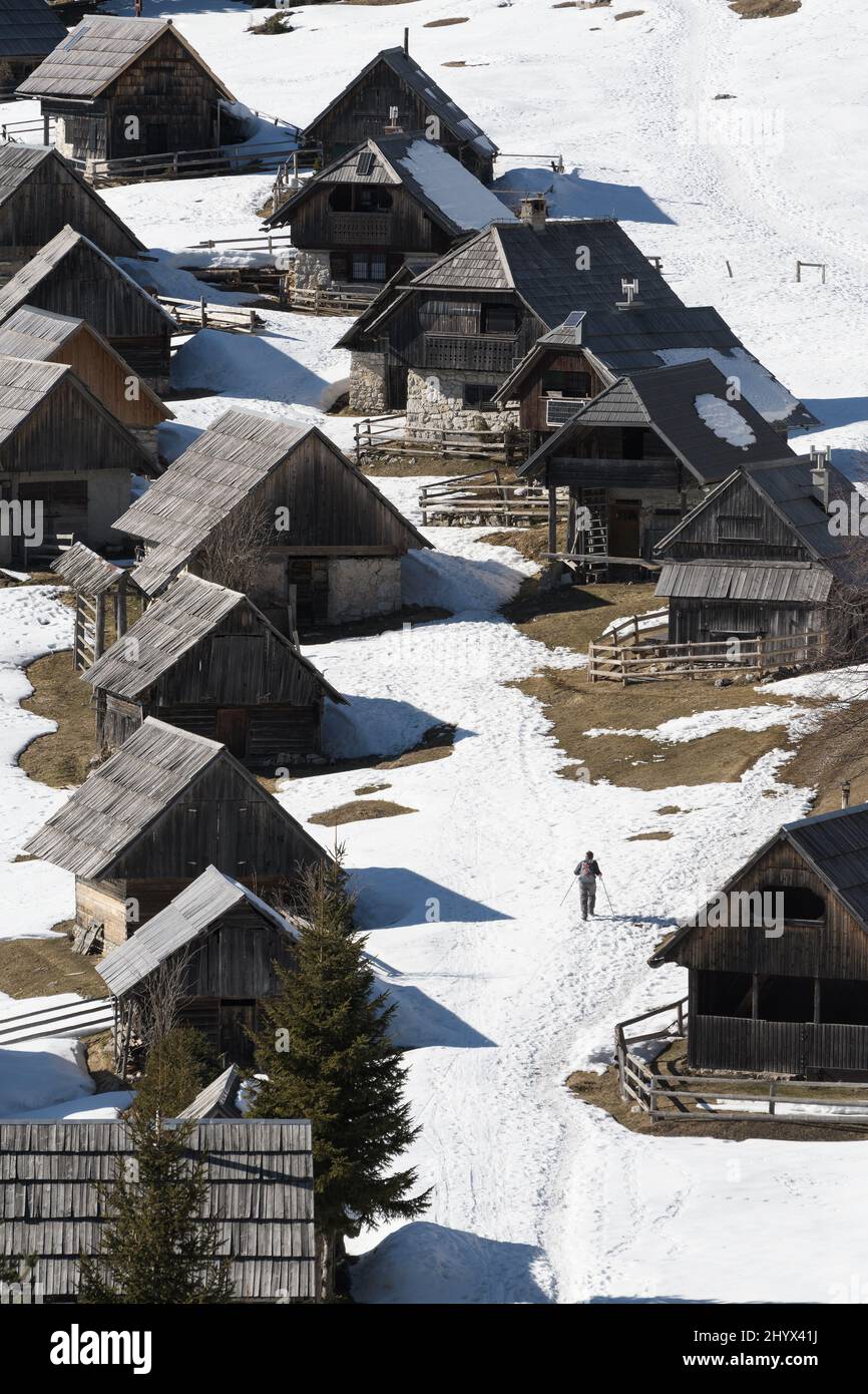 Desolate Zajamniki village and a hiker on a plateau Pokljuka in Julian Alps, Triglav national park, Slovenia Stock Photo