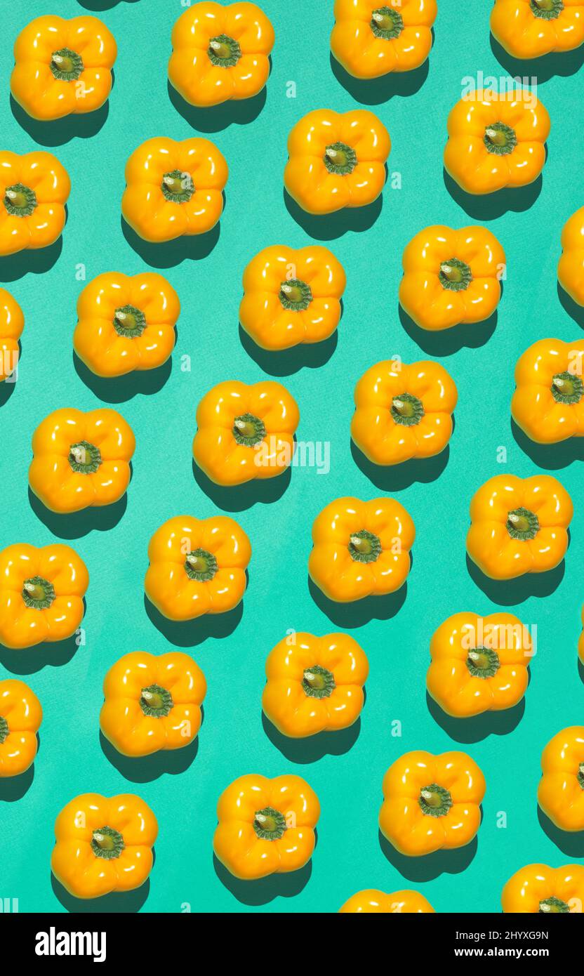 Graphic top view pattern of fresh yellow peppers in diagonal lines on contrasted blue background, healthy eating and vegan concept, copy space Stock Photo
