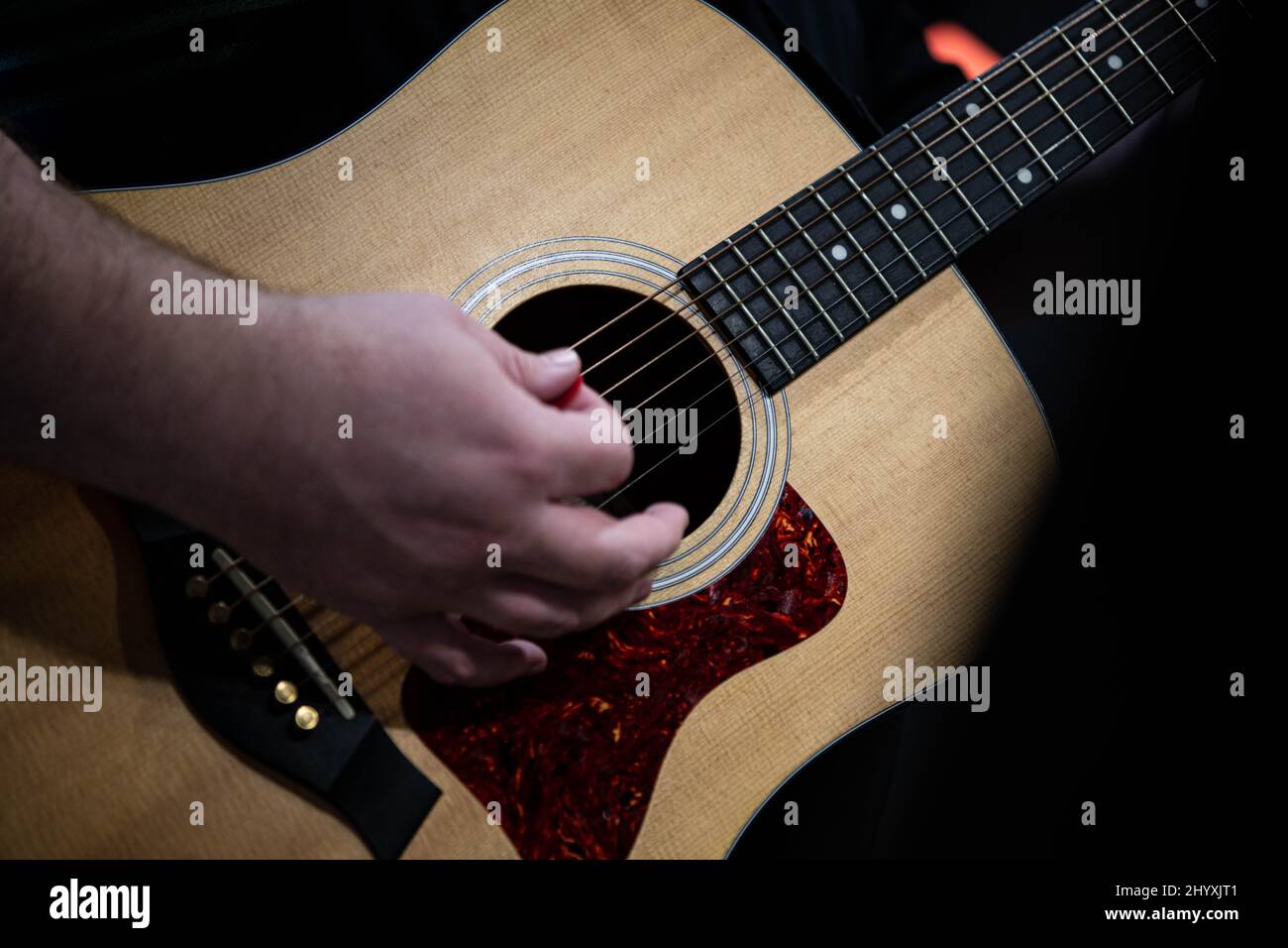 A man, guitarist, playing and strumming acoustic guitar on christian
