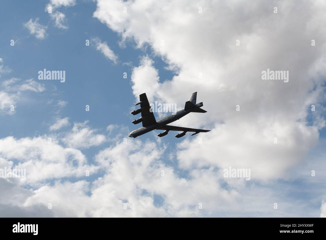 A Boeing B-52 Stratofortress bomber soars through a cloudy blue sky Stock Photo