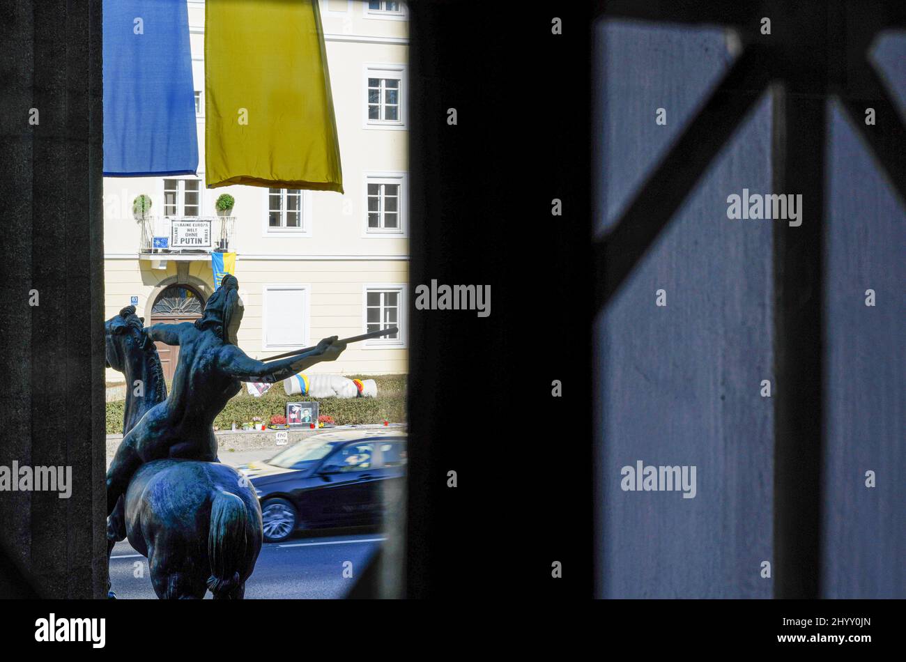 View through a window of the Museum Villa Stuck in front of which flags in the Ukrainian national colors are hanging. Stock Photo