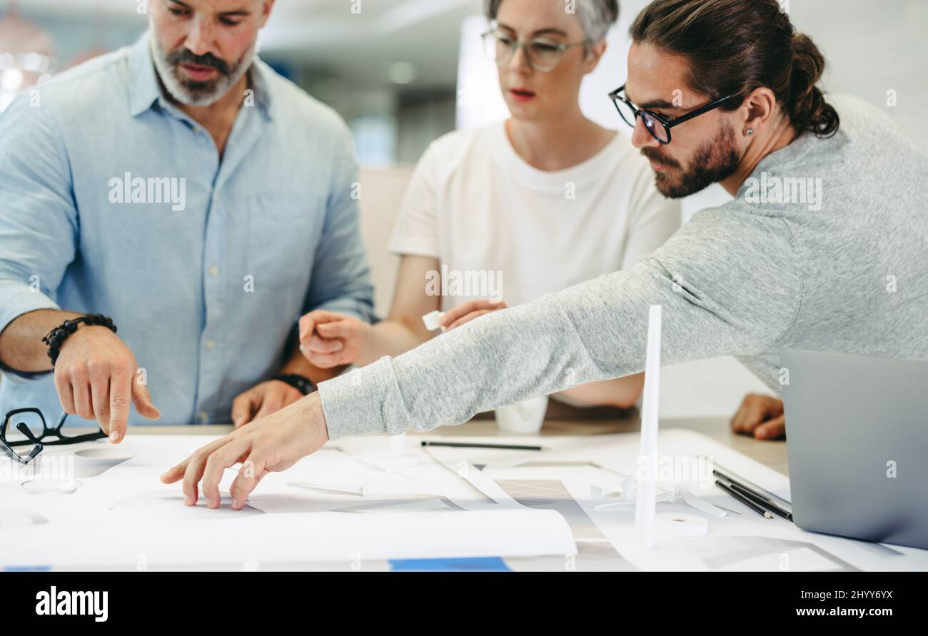 Innovative designers working with wind turbine blueprints in a modern office. Group of creative businesspeople having a discussion while working on a Stock Photo