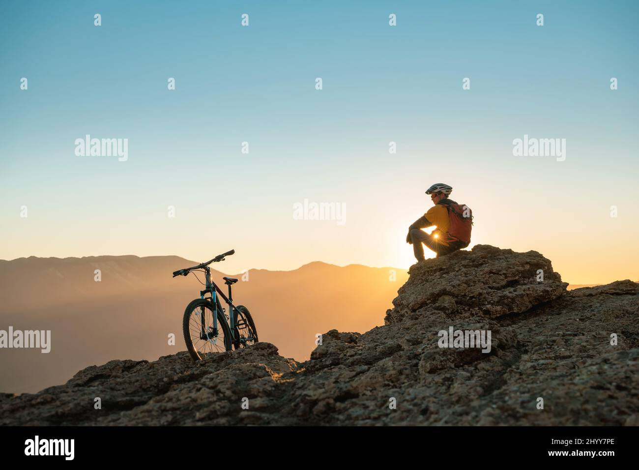 Cyclist mtb biker sits and relax on mountain top at sunset Stock Photo