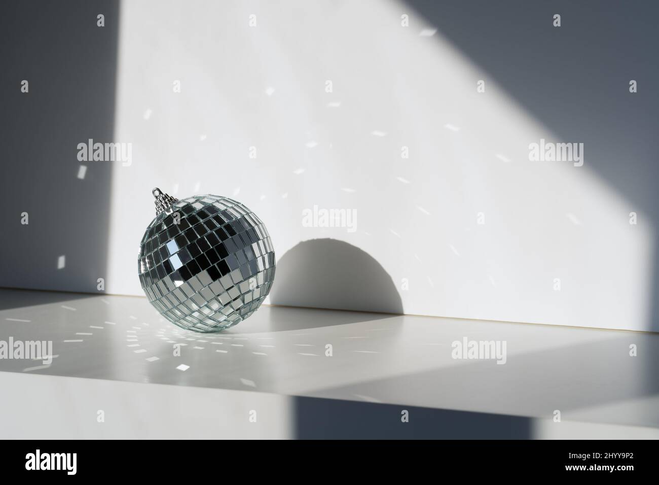 Disco ball in sunlight with reflections on white background. Geometric