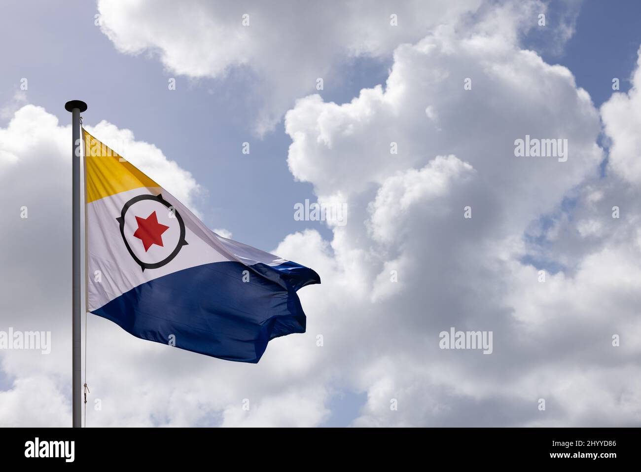 Flag of Bonaire flying in the wind on the blue sky background Stock ...