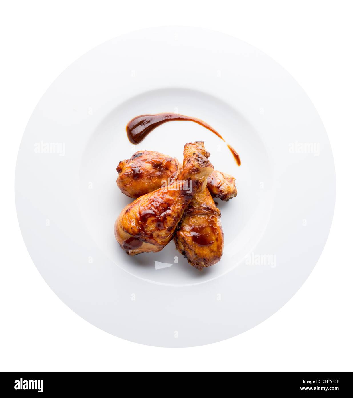 Roasted chicken legs with barbecue sause on white background plate. Top view. Aerial Stock Photo