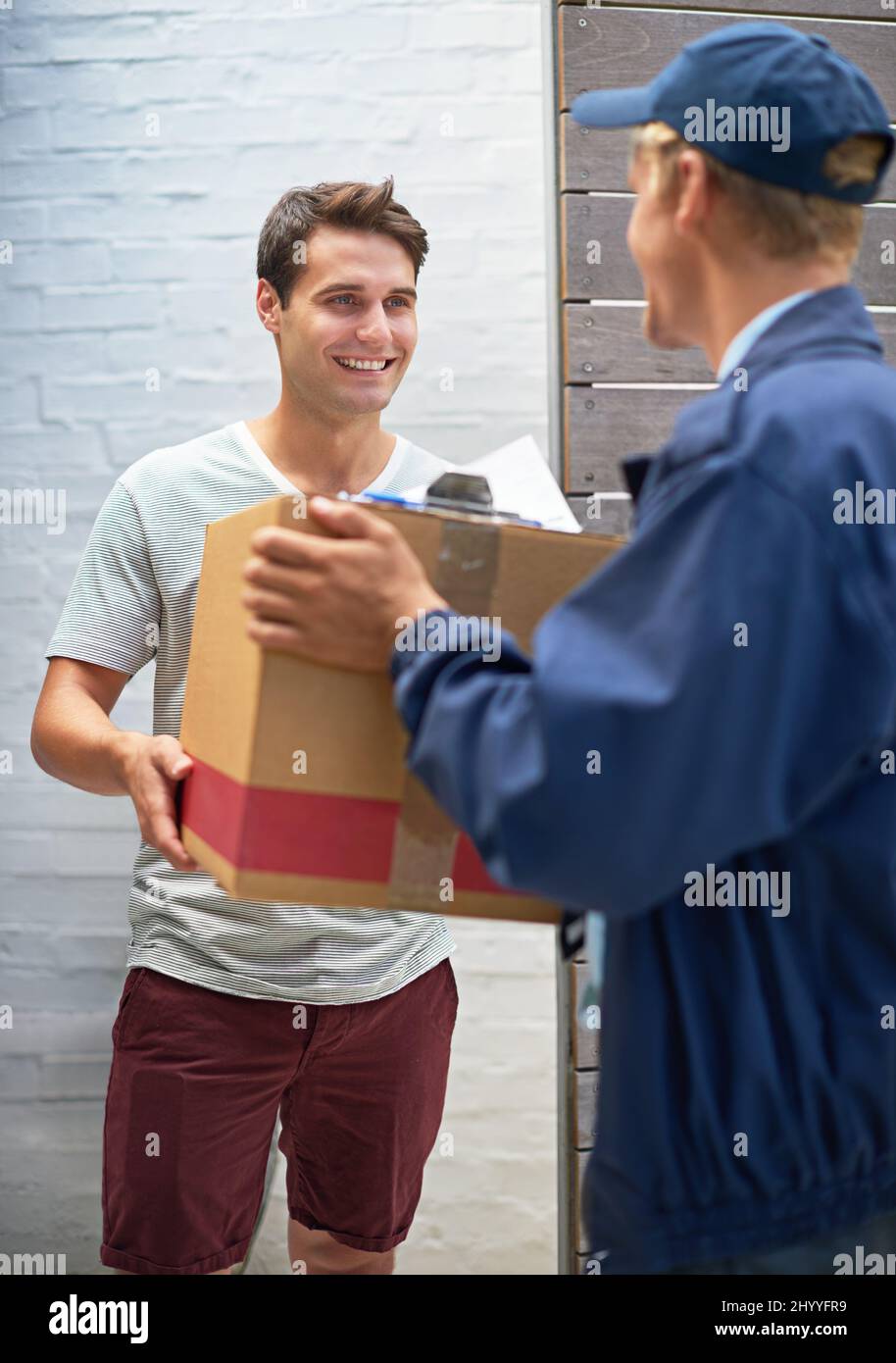 Receiving the last of his boxes. Shot of a young man receiving a cardboard box from a delivery man. Stock Photo