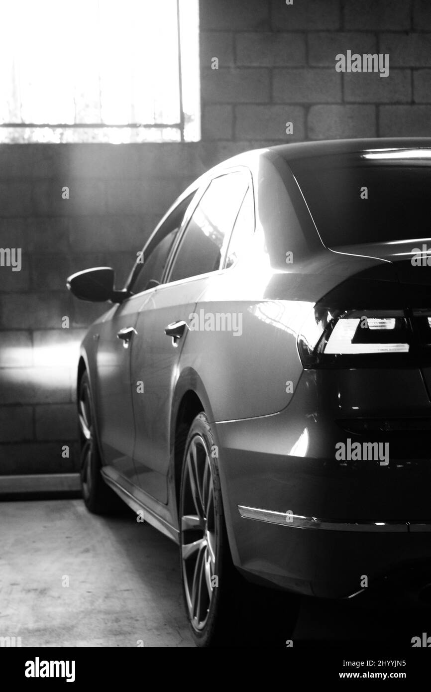 Vertical black and white shot of the back part of a car parked in a