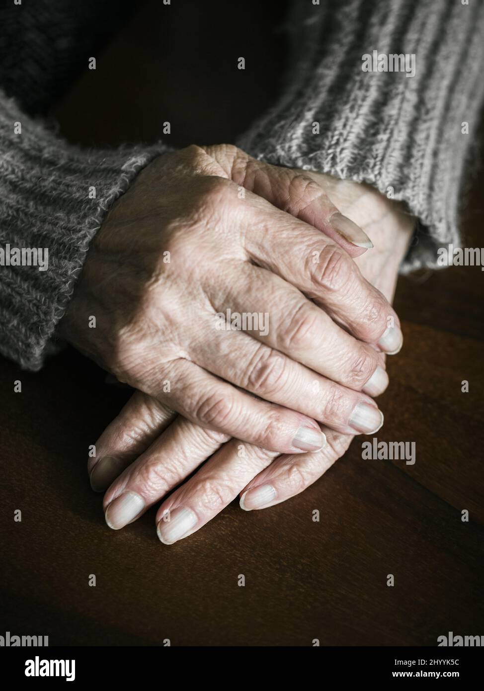 Close up of senior woman hands on table. Dramatic photography Stock Photo