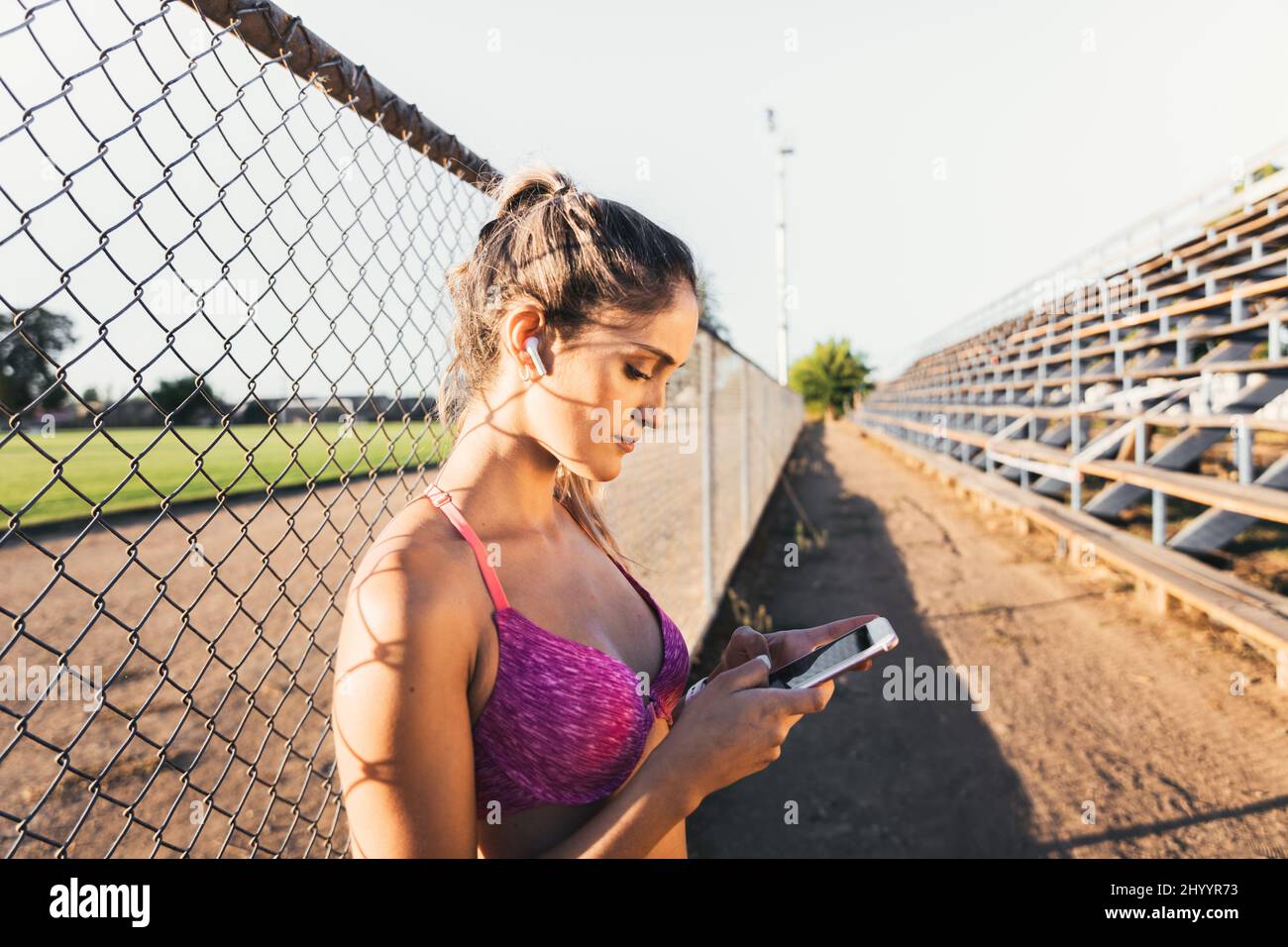 Beautiful caucasian young active woman setting a music playlist on her smartphone before start running. Stock Photo
