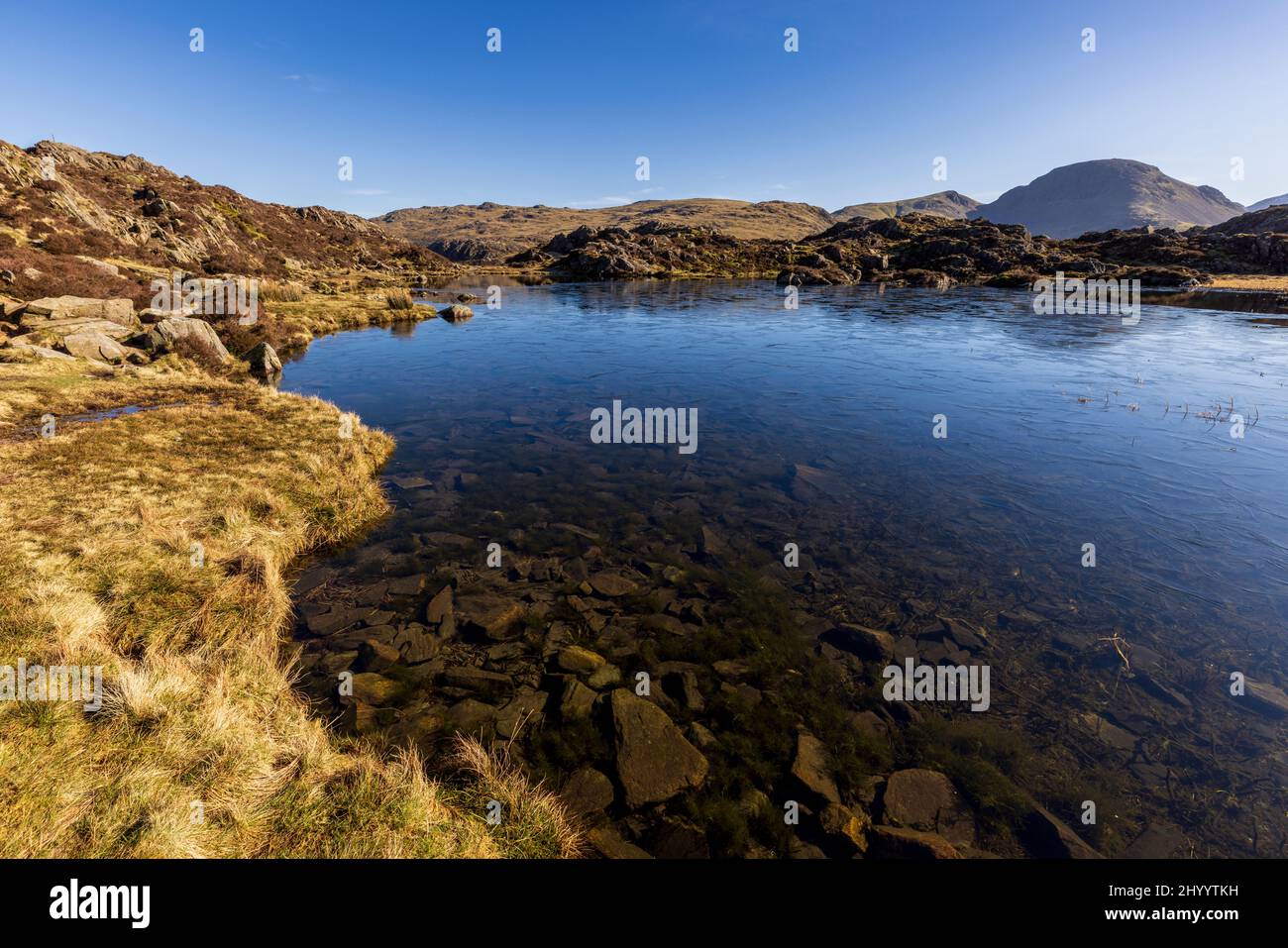 A partially frozen Innominate Tarn in winter in the Buttermere Fells, Lake District, England Stock Photo