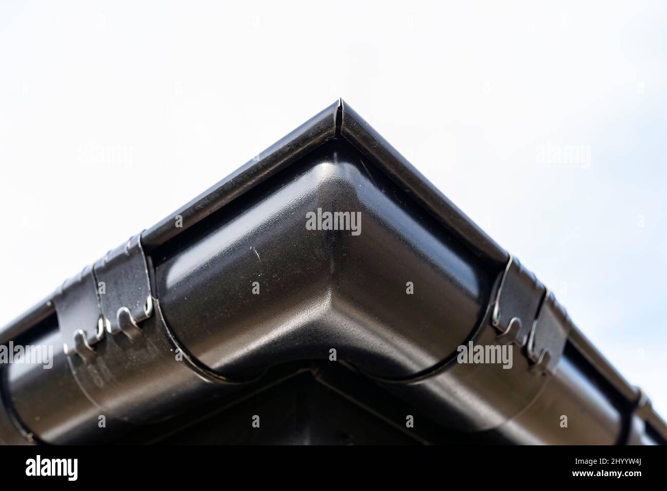 A metal, black gutter on a roof covered with ceramic tiles, visible