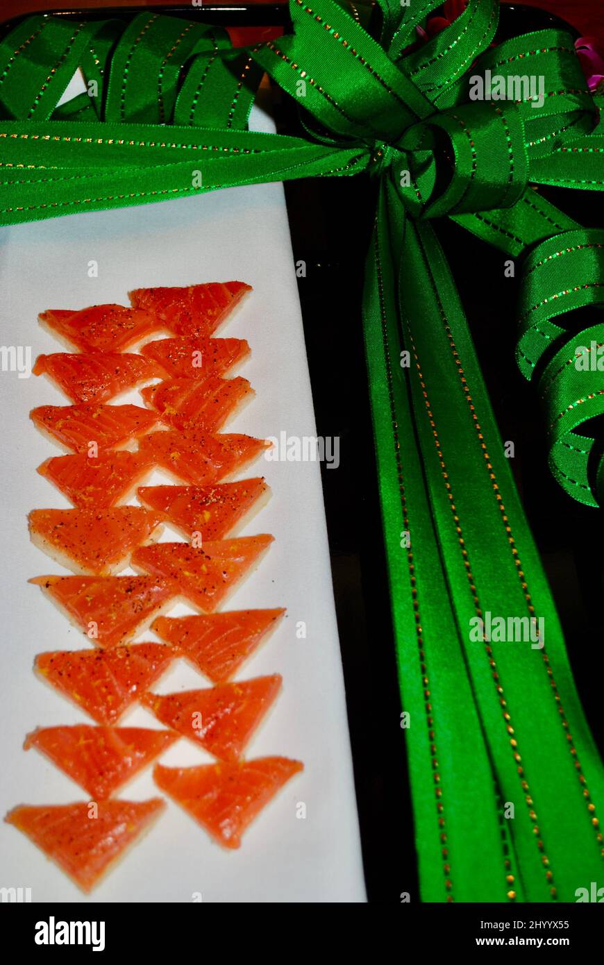 Smoked salmon on toast ocktail hors d'oeuvre served on white linen on tray decorated with green Christmas ribbon Stock Photo