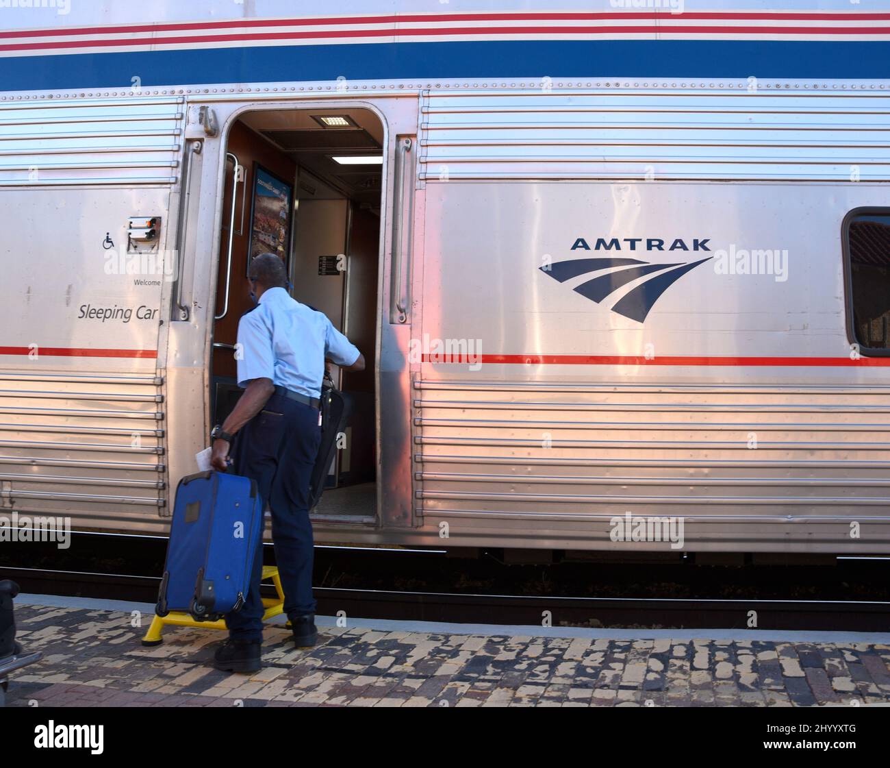 An Amtrak employee loads suitcases on an Amtrak passenger train stopped in Lamy, New Mexico, to pick up passengers. Stock Photo
