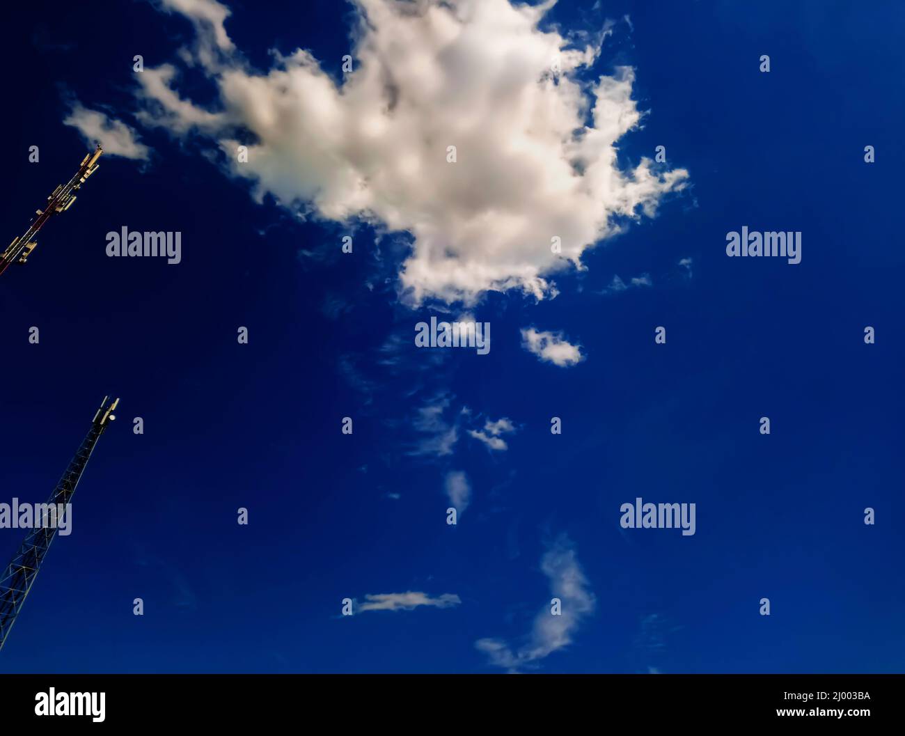 Two antennas, towers of a mobile operator against a blue sky. Blue sky with beautiful white clouds. Antennas for mobile communication, for mobile phon Stock Photo