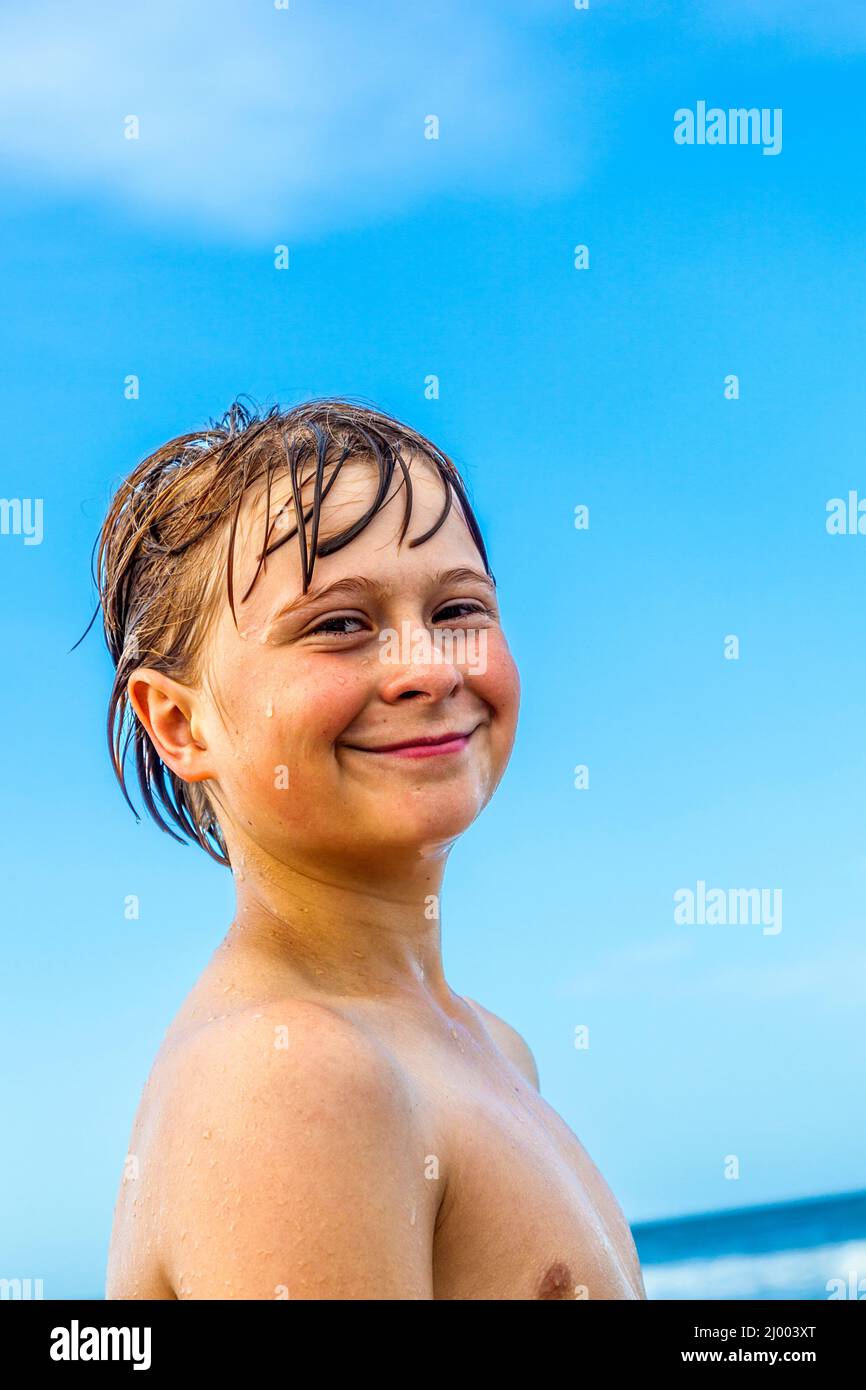 cute boy with wet hair at the beach under blue sky Stock Photo Alamy