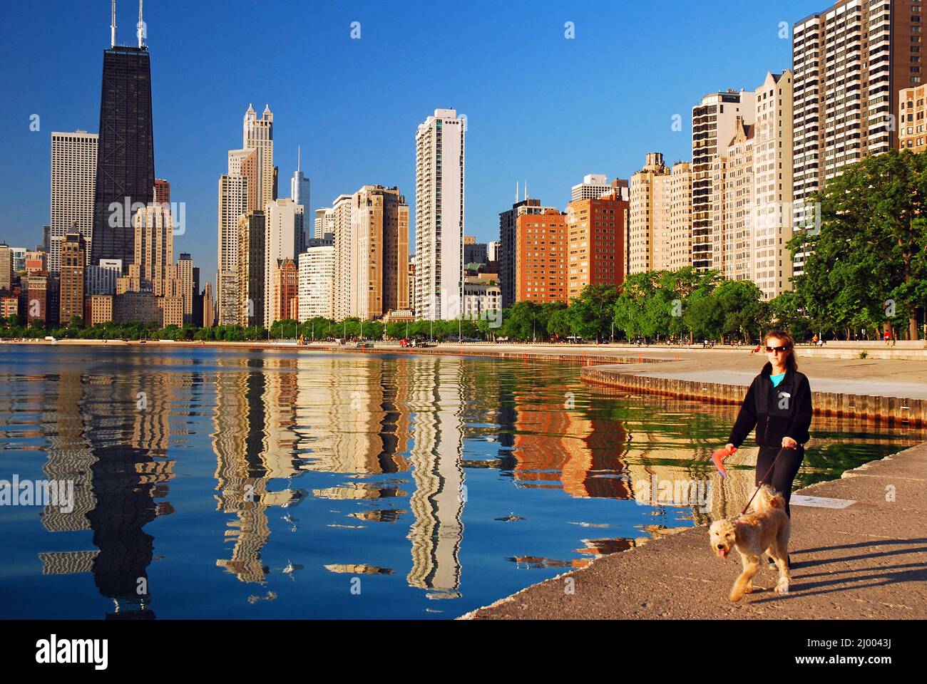 A young woman walks her dog along North Avenue Beach in Chicago Stock Photo