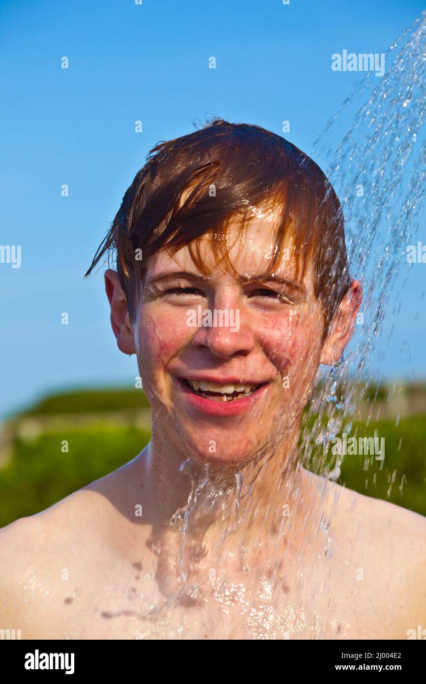 boy has a shower at the beach after swimming in the ocean Stock Photo Alamy