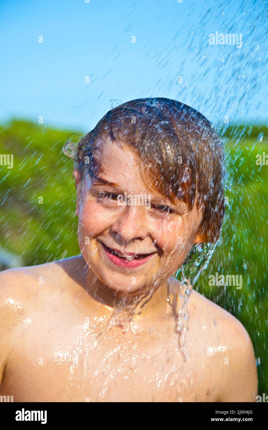 boy has a shower at the beach after swimming in the ocean Stock Photo