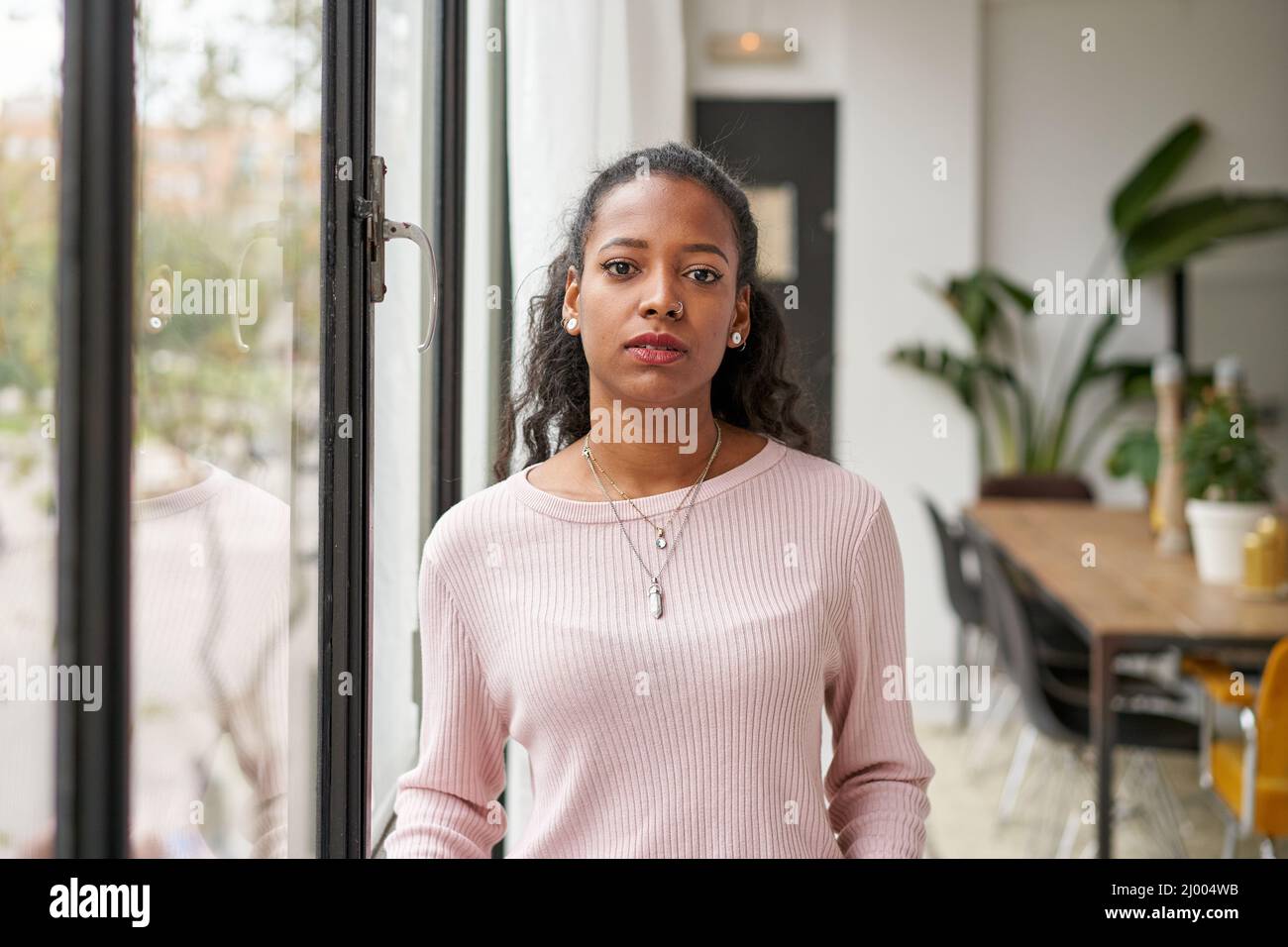 Confident beautiful African woman professional with serious face standing at home in office looking at camera. Confident entrepreneur lady posing Stock Photo