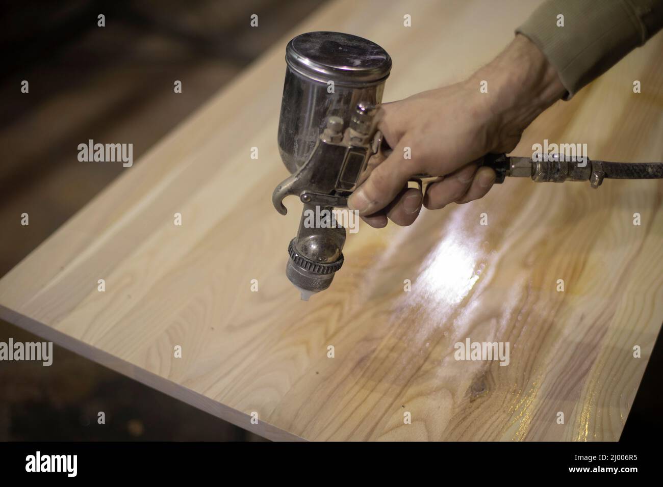 Applying varnish to board. Spray gun for paint supply. Instrument is in