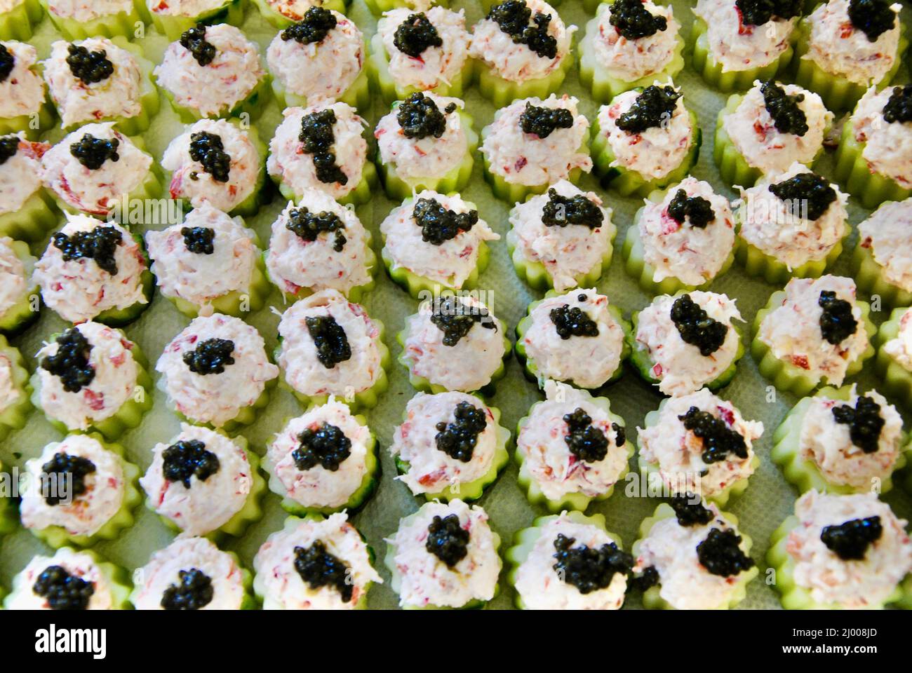 Cucumber cups filled with lobster salad topped with black caviar prepared for a large event Stock Photo