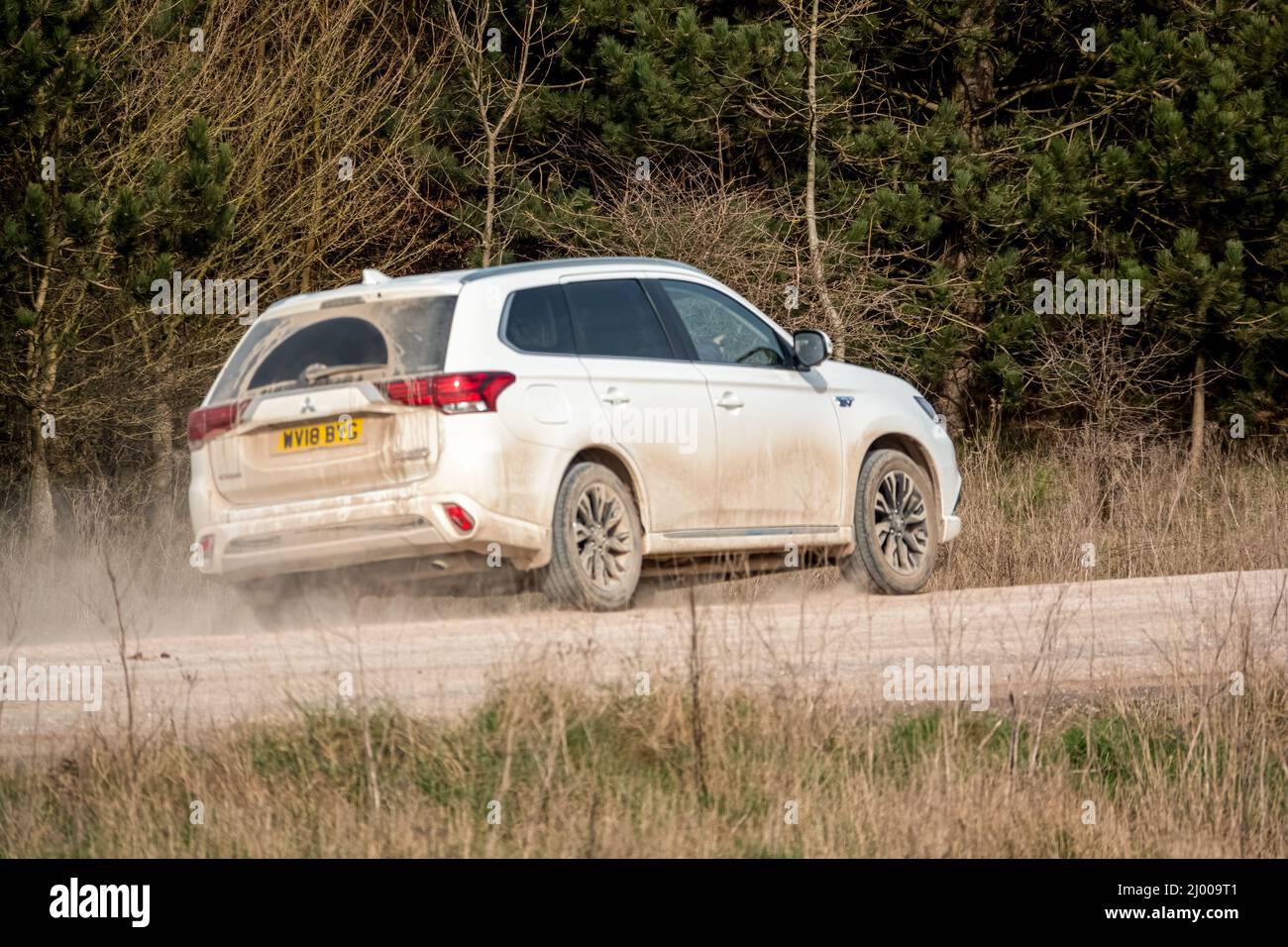 Black Peugeot 5008 GT sport utility vehicle driving along an unmade stone track road thowing up dust Stock Photo