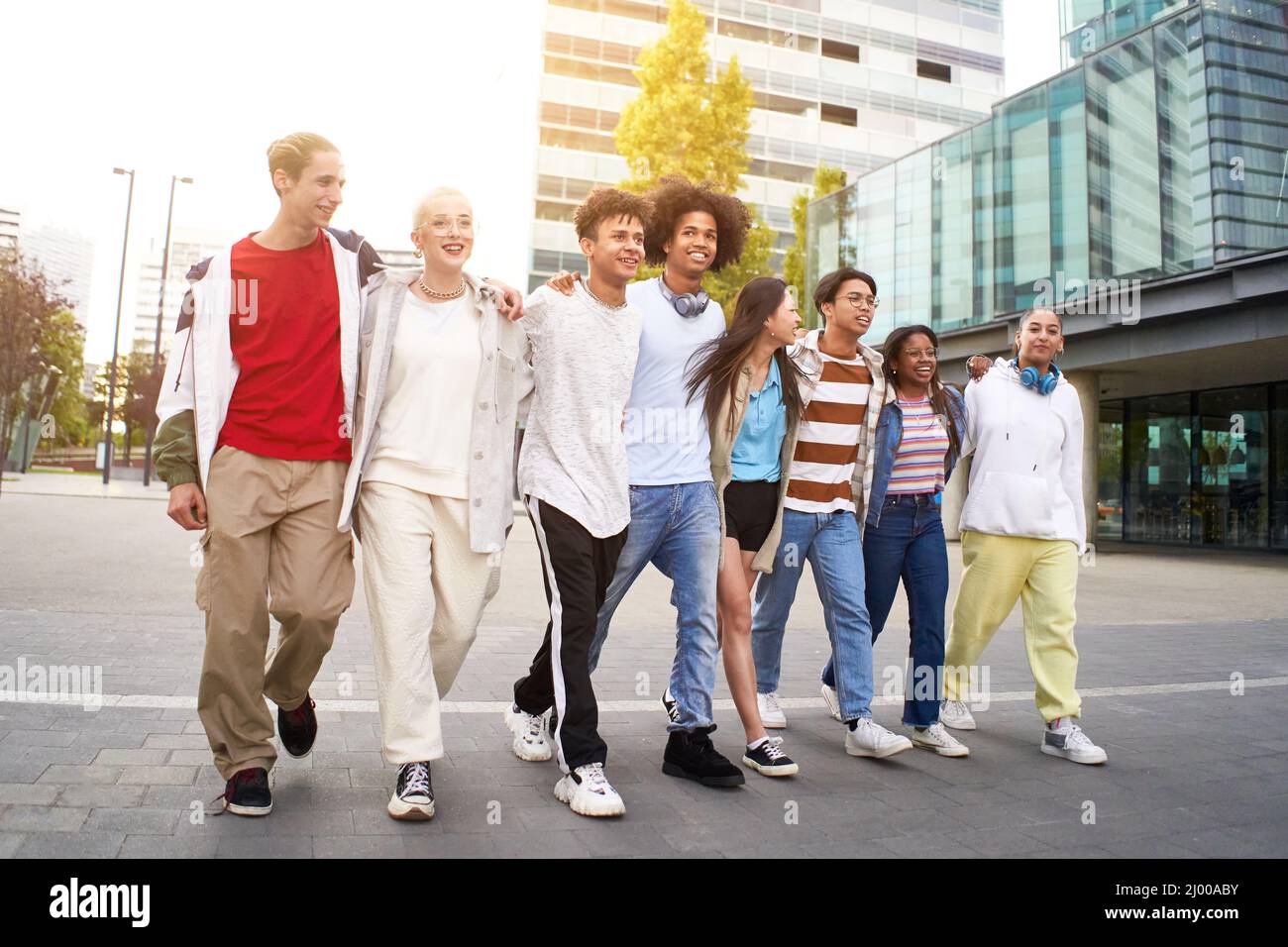 Smiling multiracial young people walking and hugging in the city. Group of happy teenagers friends having fun together outdoors. Stock Photo