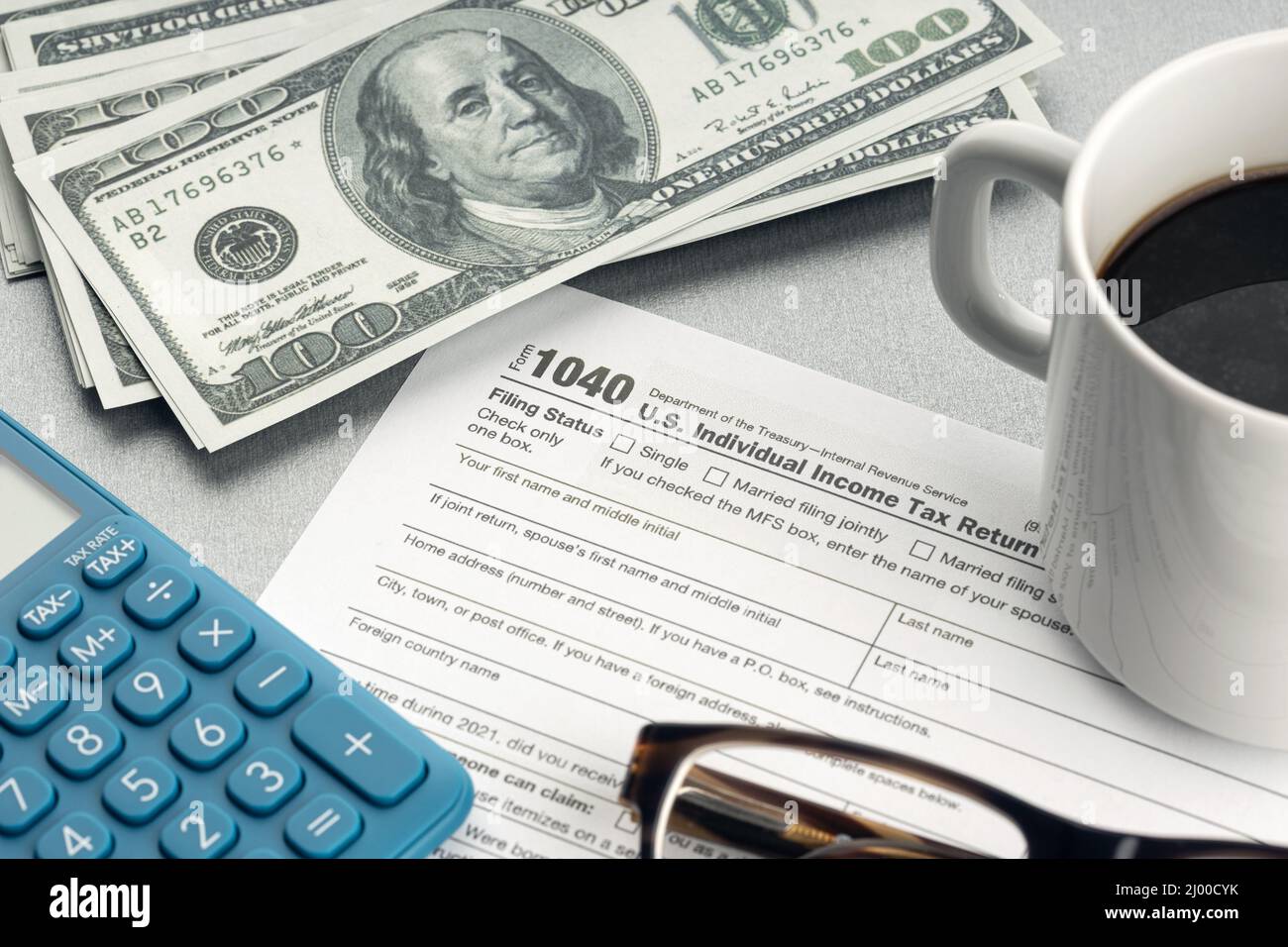 Tax form, calculator, eyeglasses and money on desk. Tax time concept Stock Photo