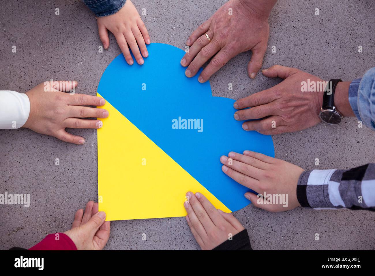 Human hands around a heart with the colors of the Ukrainian flag. Unity, solidarity and support for Ukraine. No to war. Stock Photo