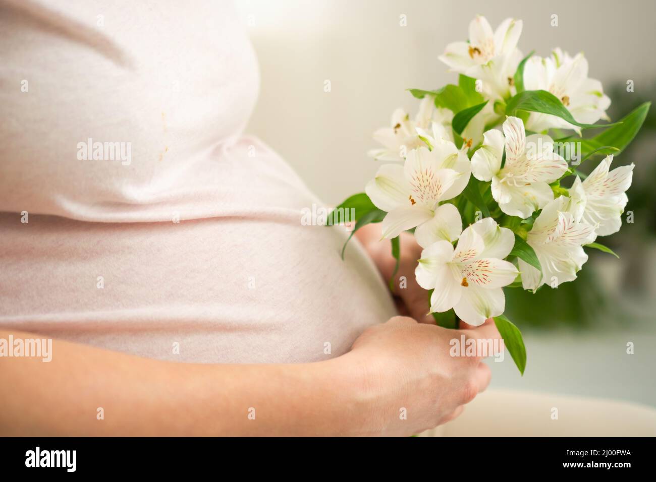 Beautiful pregnant woman with a bouquet of flowers in her hand strokes