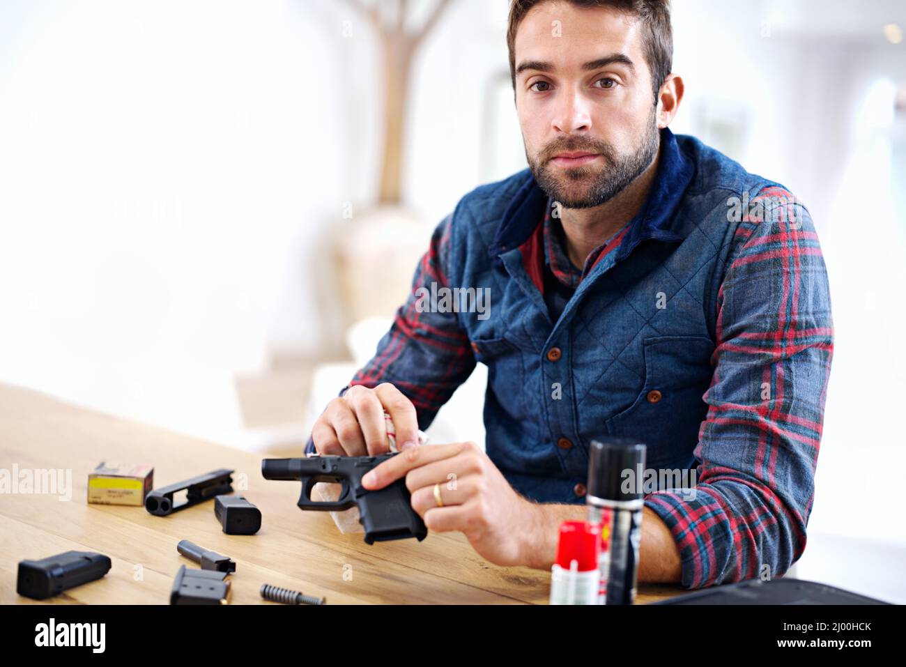 Regular maintenance is essential for every gun owner. A young man cleaning his gun. Stock Photo