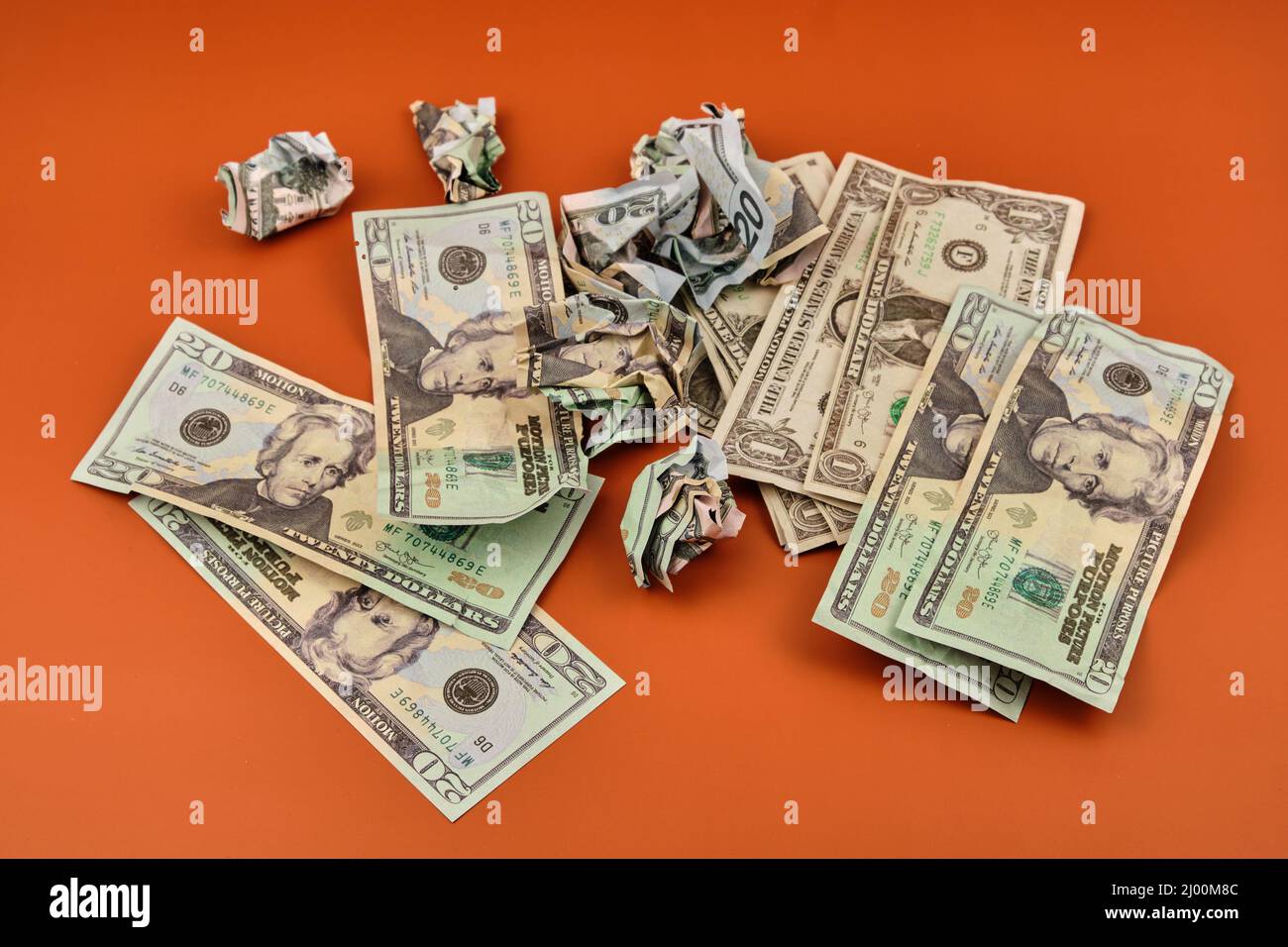 A pile of crumpled and dirty dollar bills lying on an orange table