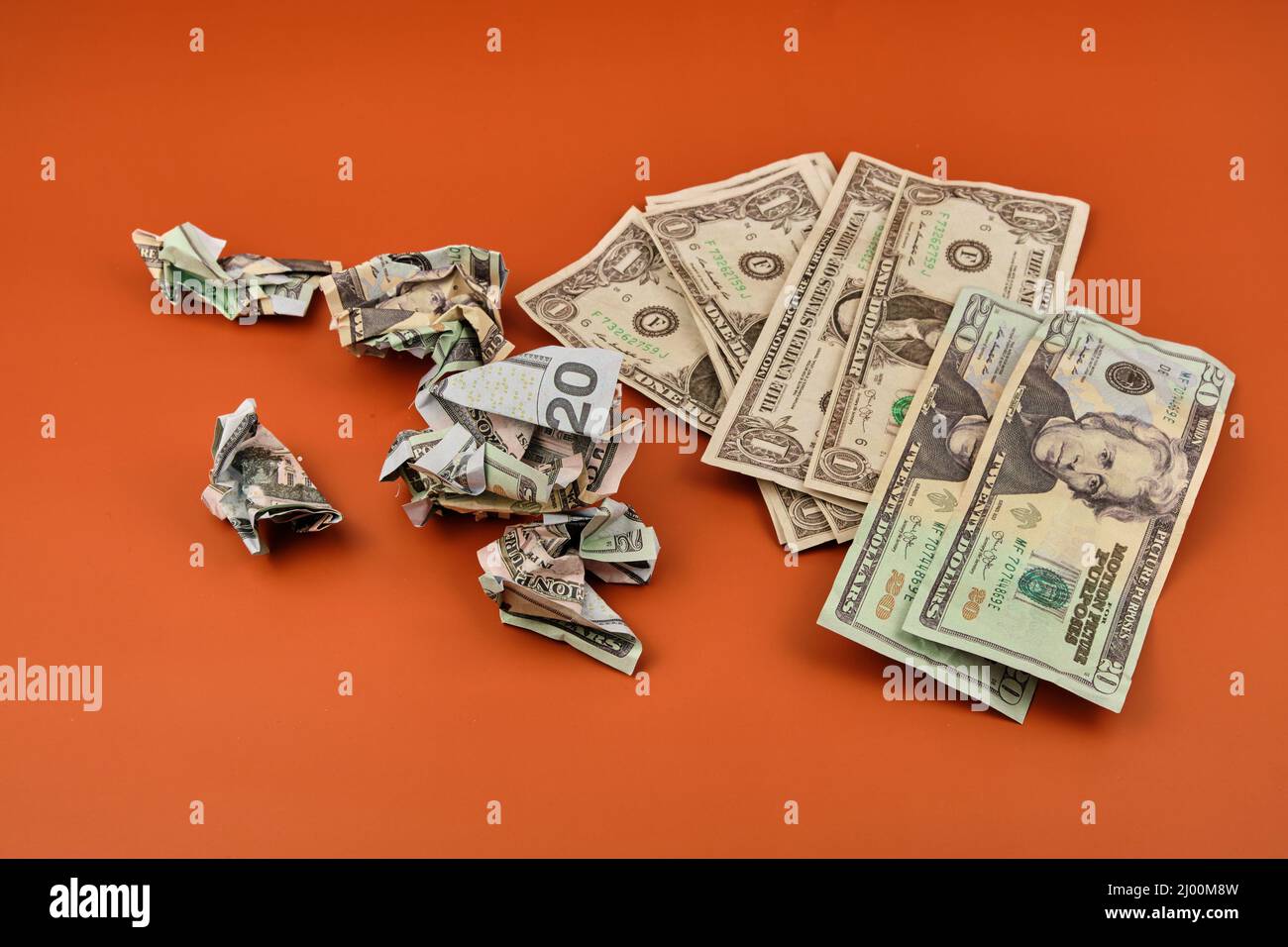A pile of crumpled and dirty dollar bills lying on an orange table. Dirty money concept. Stock Photo