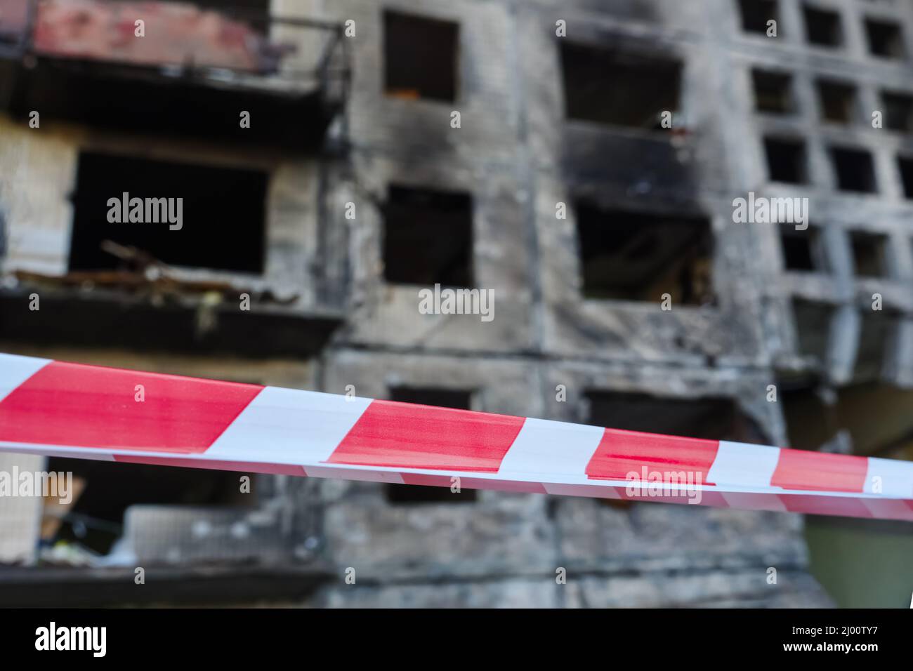 2022 Russian invasion of Ukraine bombed building destroyed warning tape foreground. Rocket bomb attack Russia against Ukraine war destruction building Stock Photo