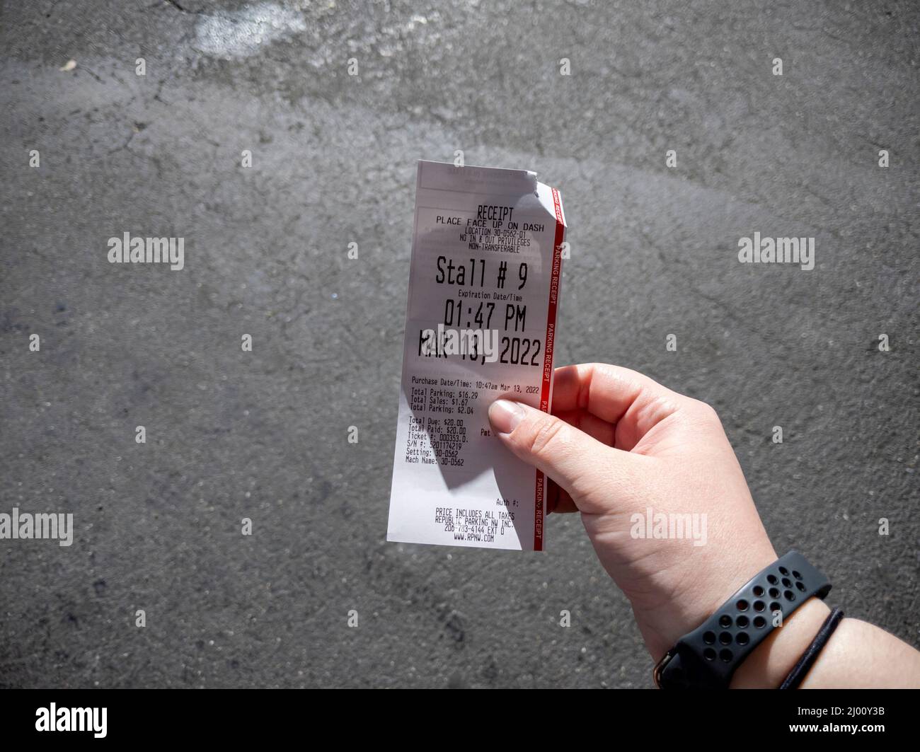 Seattle, WA USA - circa March 2022: View of a Caucasian female hand holding a parking receipt to place on a car dashboard in the downtown Seattle area Stock Photo