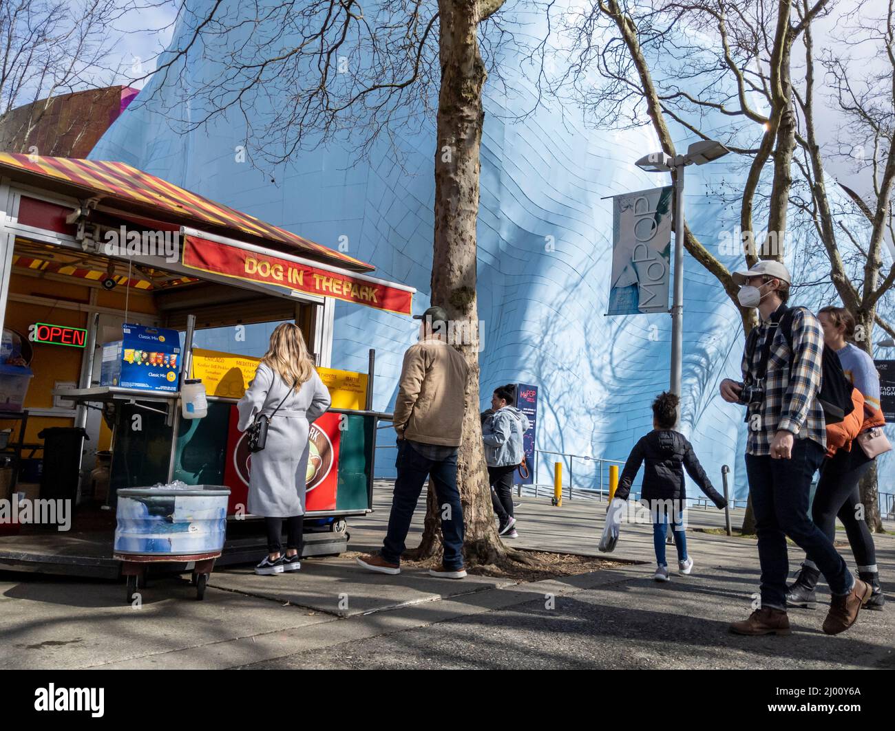 Seattle, WA USA - circa March 2022: People waiting in line to buy food from a hot dog cart in downtown Seattle, near the Space Needle and Chihuly Gard Stock Photo