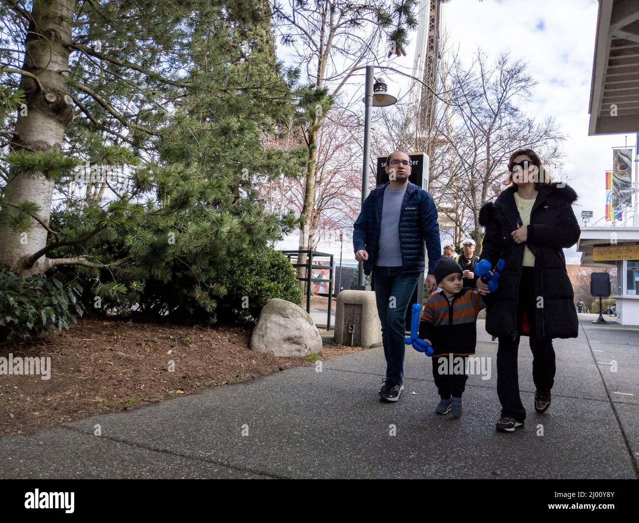 Seattle, WA USA - circa March 2022: Caucasian man and woman walking with their child around downtown Seattle, near the Space Needle and Chihuly Garden Stock Photo