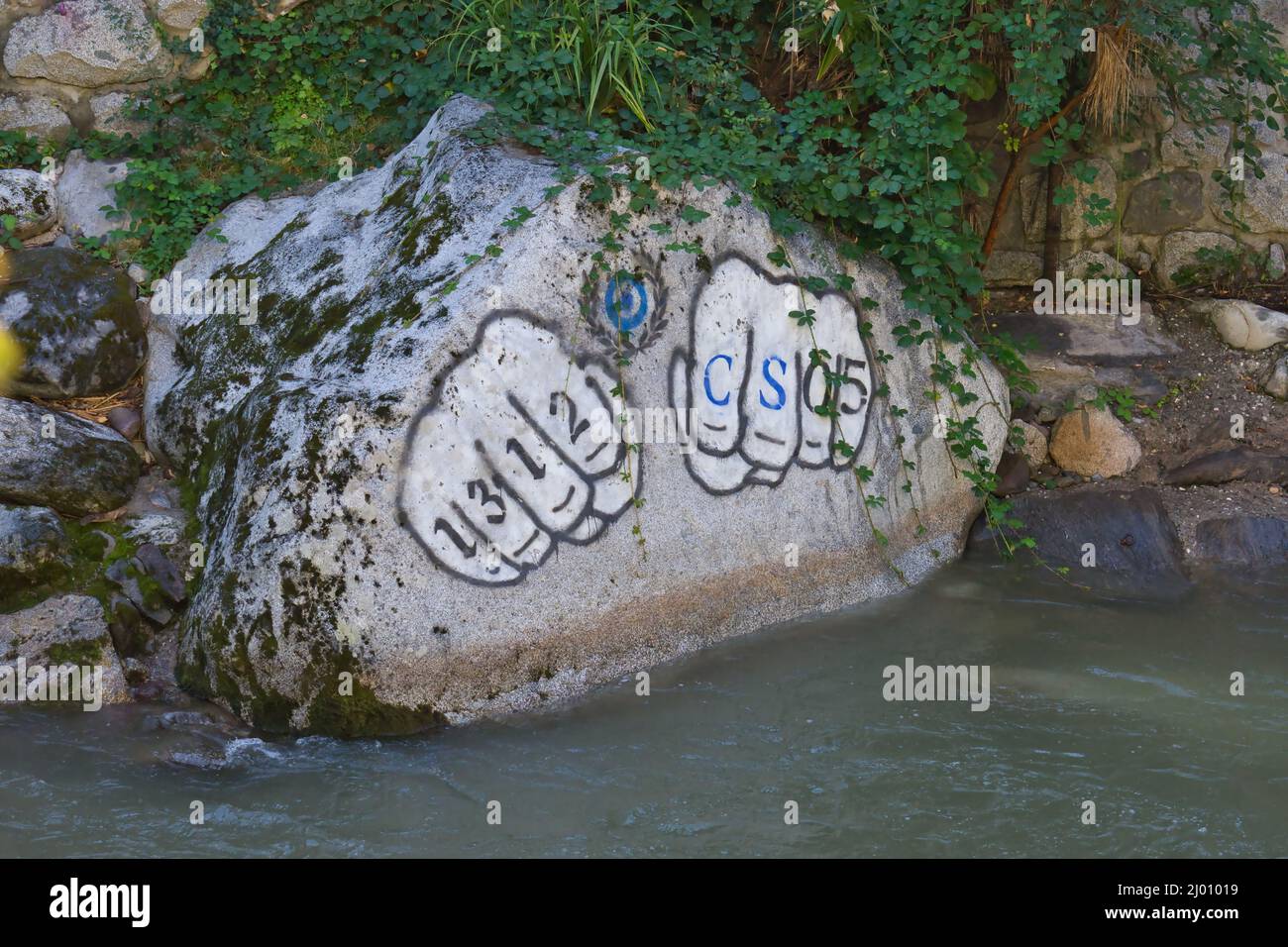 A rock painted with two fists and an inscription in the Passer river in ...