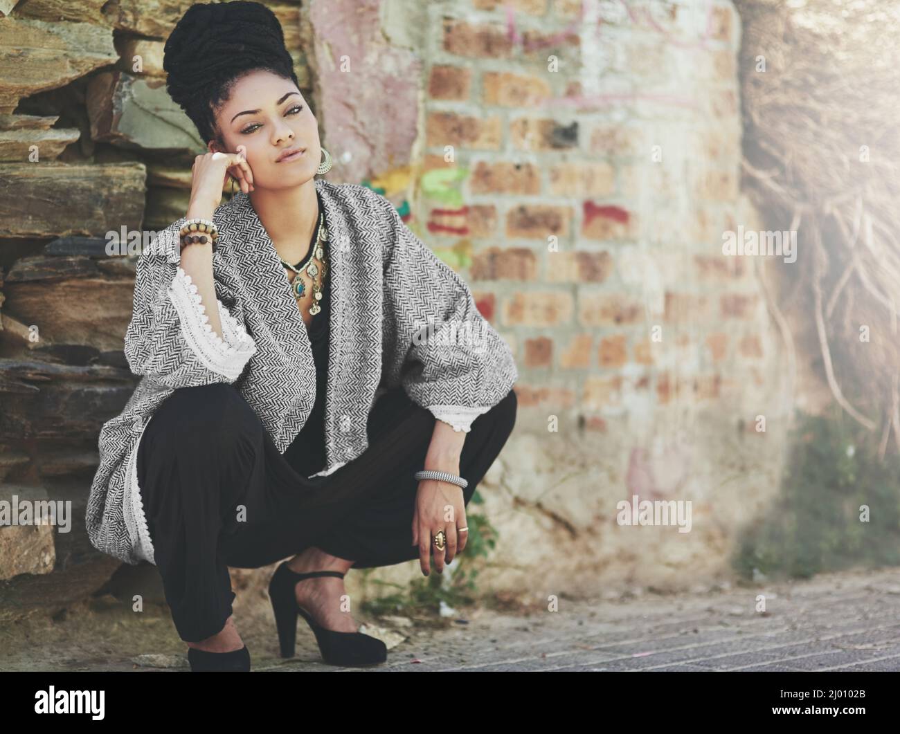 High heels, high hopes. Full length shot of a fashionable young woman crouching against a wall. Stock Photo