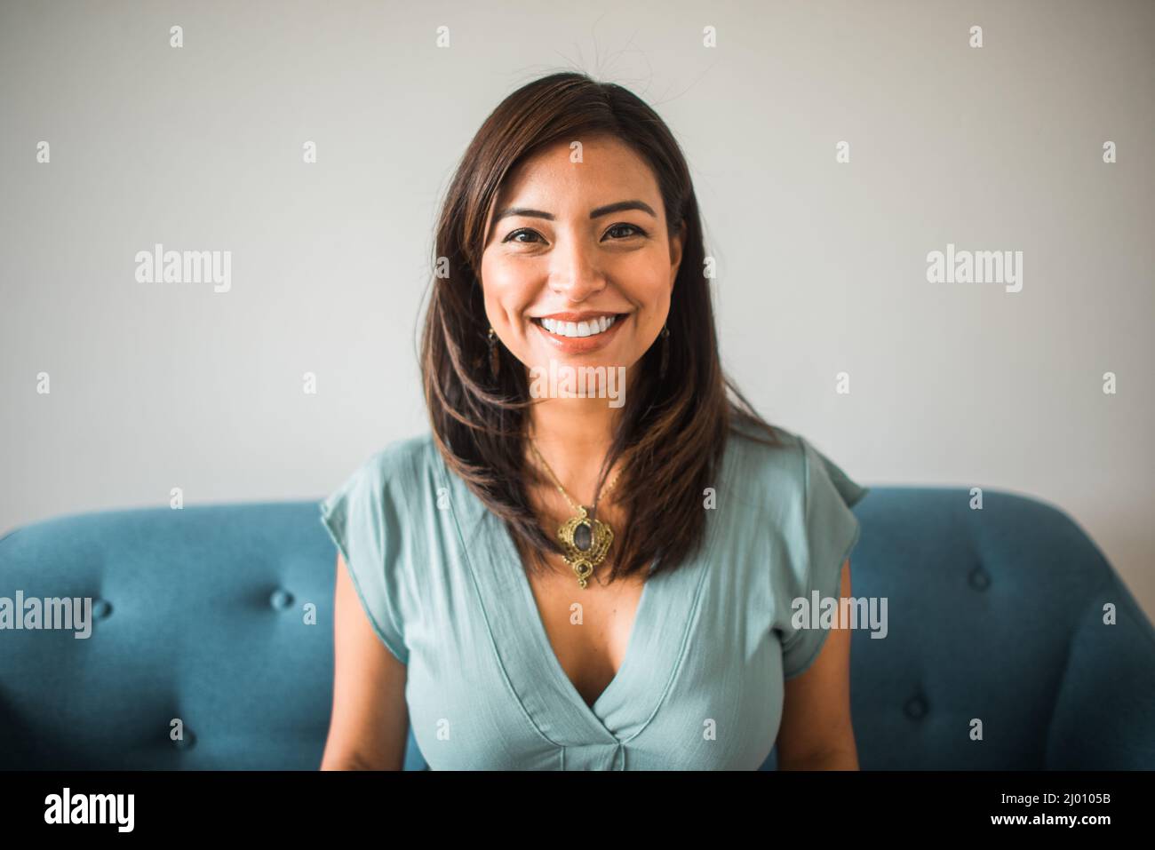 portrait of a smiling woman looking at the camera sitting on the sofa at home Stock Photo