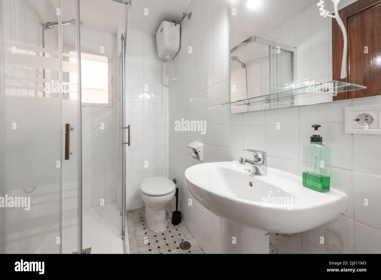 Bathroom with white porcelain sink with mirror and glass shelf and shower cubicle to one side