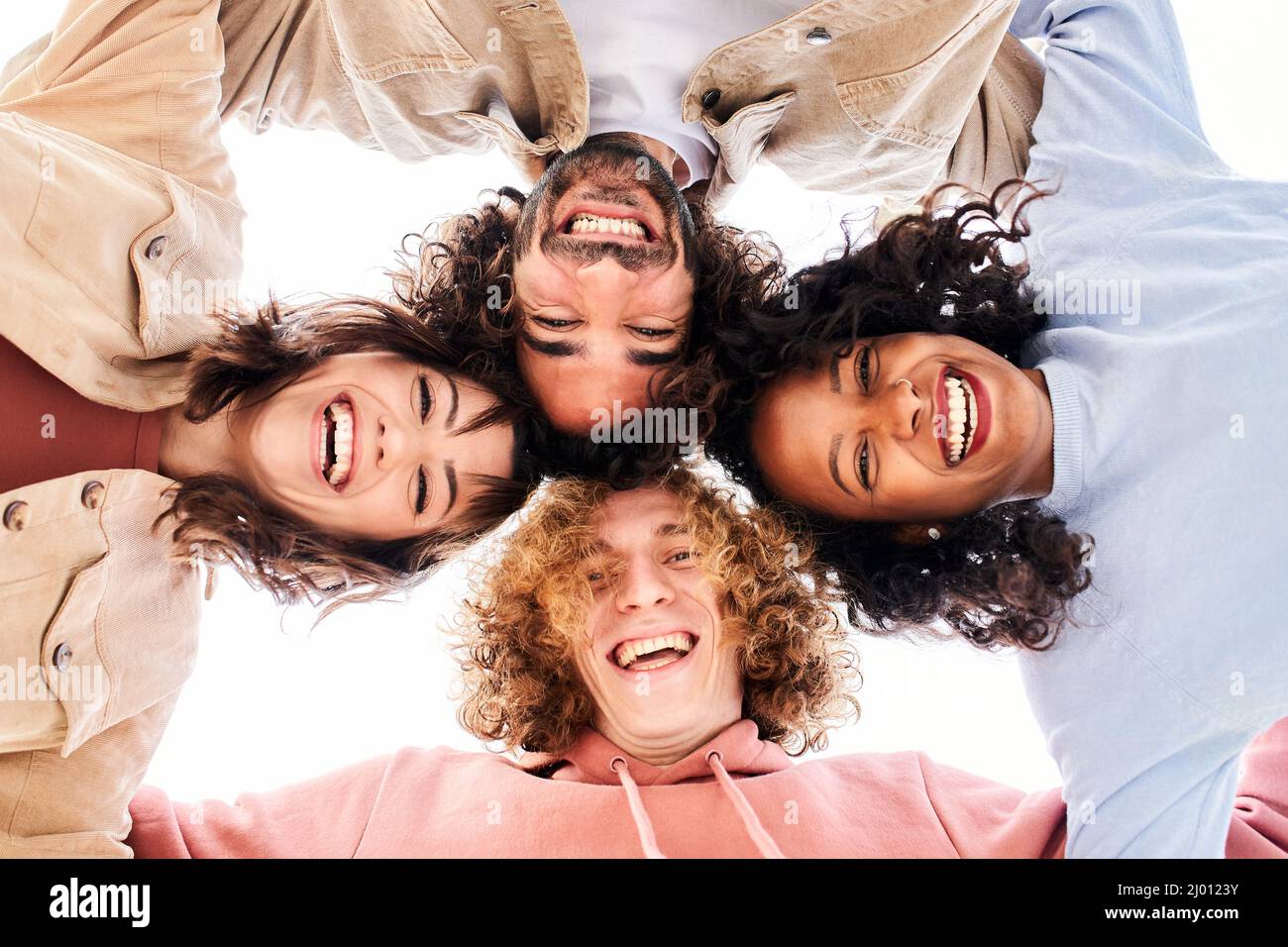 Team of happy young people looking at the camera embracing and having a fun. Smiling cheerful friends. Stock Photo